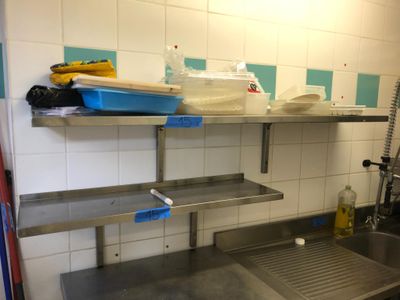 une cuisine équipée d'un évier et d'une étagère en métal