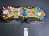 two boxes of pokemon cards sitting on top of a table
