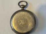a silver pocket watch on a table with a white background