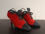 une paire de chaussures rouges et noires avec des lacets noirs posée sur une table