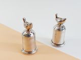 two silver pepper shakers sitting next to each other on a table