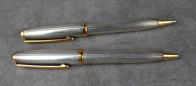 deux stylos à plume argentés et dorés posés sur une table