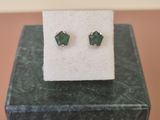 une paire de boucles d'oreilles vertes posée sur un bloc de marbre