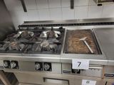 une cuisinière avec une casserole posée dessus, dans une cuisine