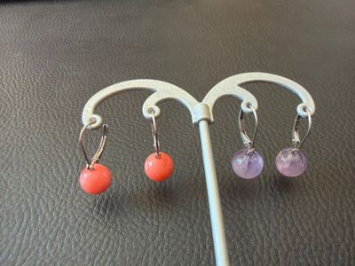 three pairs of earrings hanging from a hook on a table