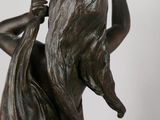 bronze statue of a woman holding her hands up in the air