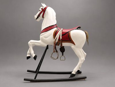 statue d'un cheval blanc avec une selle rouge, posée sur un socle noir