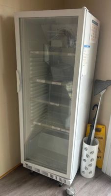 a glass door refrigerator sitting in the corner of a room