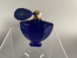 blue glass perfume bottle with a gold top on a clear display case