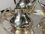 a silver plate with a silver tea pot and a silver tea pot on it