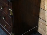 a wooden dresser with a black marble top and brass handles