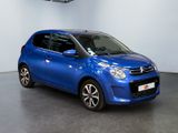 the small blue car is parked in a large room