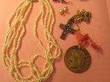 une photo représentant un collier, une pièce de monnaie et d'autres bijoux posés sur un fond rose