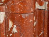 a close up of a red marble column with a clock on it