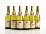 six bouteilles de vin blanc alignées sur une surface blanche