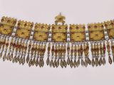 un gros plan d'un collier doré et rouge posé sur une surface blanche
