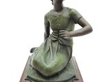 statue d'une femme en robe verte, assise sur un socle en bois