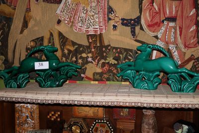 deux statues vertes représentant des animaux, posées sur une étagère devant un tableau