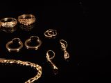 a lot of gold rings and bracelets on a black surface