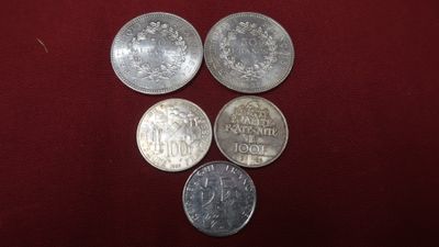 a group of five coins sitting on top of a red cloth