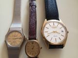 Trois montres différentes sont posées les unes à côté des autres sur une table.