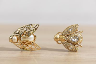 deux paires de boucles d'oreilles en forme d'abeille, en or et diamants, posées sur une surface en bois