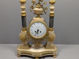 une horloge en or posée sur une table blanche