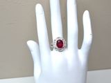 a hand with a ring on it that has a red stone in it