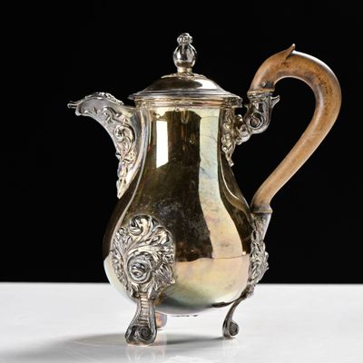 an antique silver coffee pot with a wooden handle on a white table