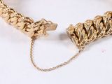 gold bracelet with a chain and a clasp on a white surface