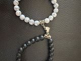 un bracelet en perles noires et blanches orné d'un pendentif en forme de crâne