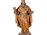 une vieille statue en bois représentant un homme coiffé d'un chapeau et vêtu d'une robe