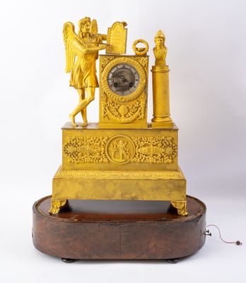 une horloge dorée posée sur un socle en bois, sur fond blanc