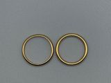 une paire de boucles d'oreilles créoles en or posées sur une surface grise