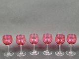 six verres à vin roses alignés sur une surface grise