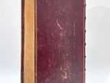 an old book sitting on top of a white table next to a white wall