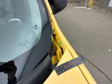 a close up of a yellow car with a sticker on it ' s windshield