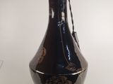 un vase noir orné de motifs dorés, posé sur une table