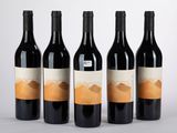 quatre bouteilles de vin sont alignées sur une surface blanche