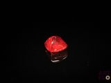 un diamant rouge sur une surface noire dans l'obscurité