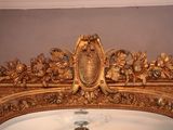 a mirror with a gold frame and a clock on it