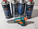 four cans of butane gas and a glue gun on a table
