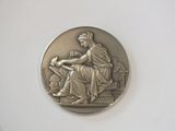 une image représentant une médaille d'argent sur laquelle figure une femme assise sur une chaise