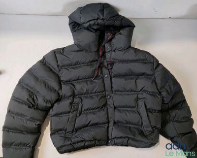 La veste est noire et comporte une capuche fixée à l'arrière de la veste.