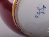 a close up of a red vase with a gold rim