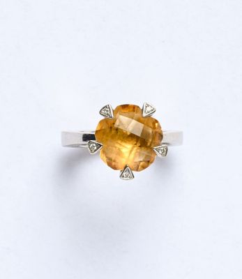 une bague sertie d'un saphir jaune et de diamants, sur fond blanc