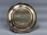 an antique silver plate on a stand on a gray surface
