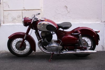 a red motorcycle parked in front of a white wall