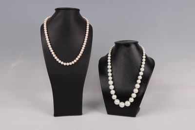 une paire de colliers de perles et un collier posé sur un présentoir pour mannequin