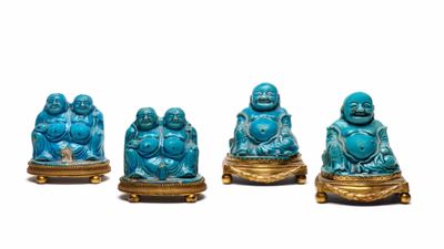 Quatre figurines de Bouddha bleues sont posées sur un socle doré